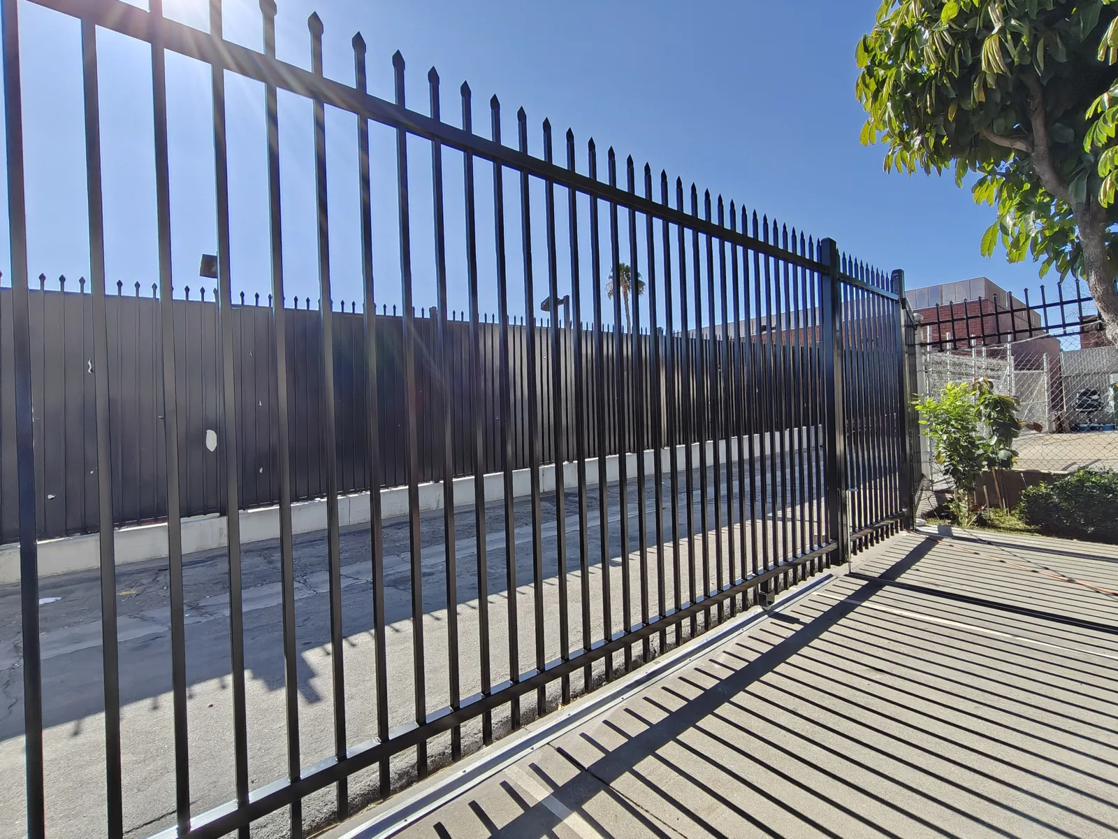 Long run of black spear-top steel security fence at a Los Angeles commercial yard