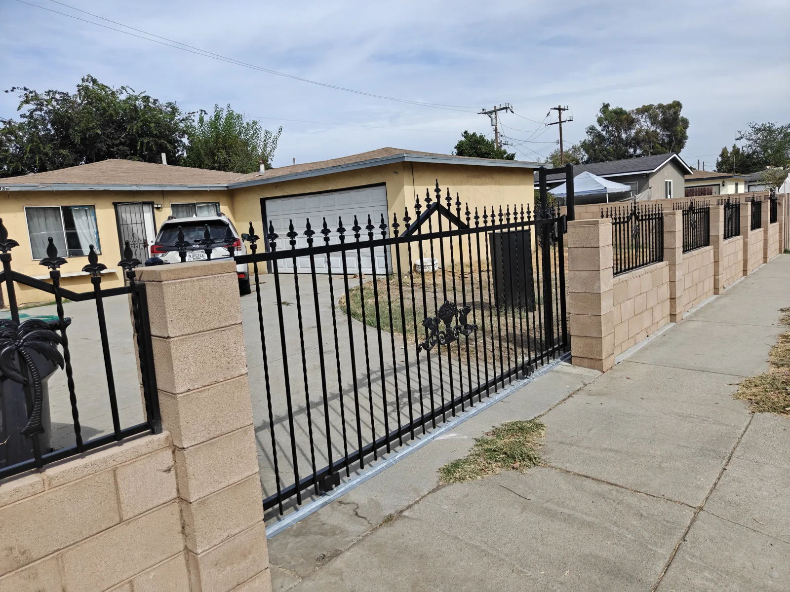 Long run of ornamental iron fence on a block wall along the sidewalk in Baldwin Park, CA by Apexguard Fence
