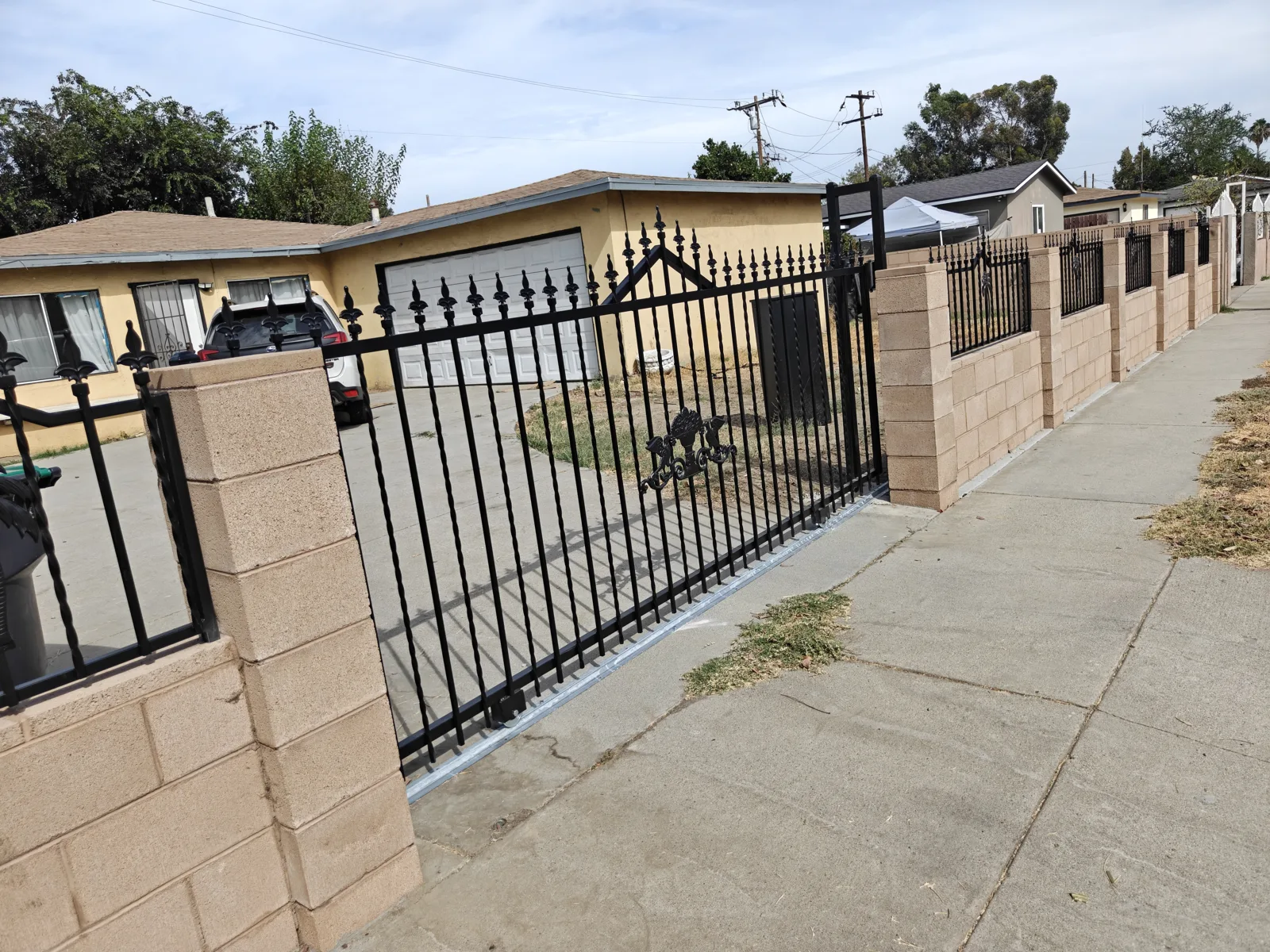 4 ft ornamental wrought iron fence with fleur-de-lis finials on a tan block wall — a real Apexguard Fence project in Baldwin Park, CA