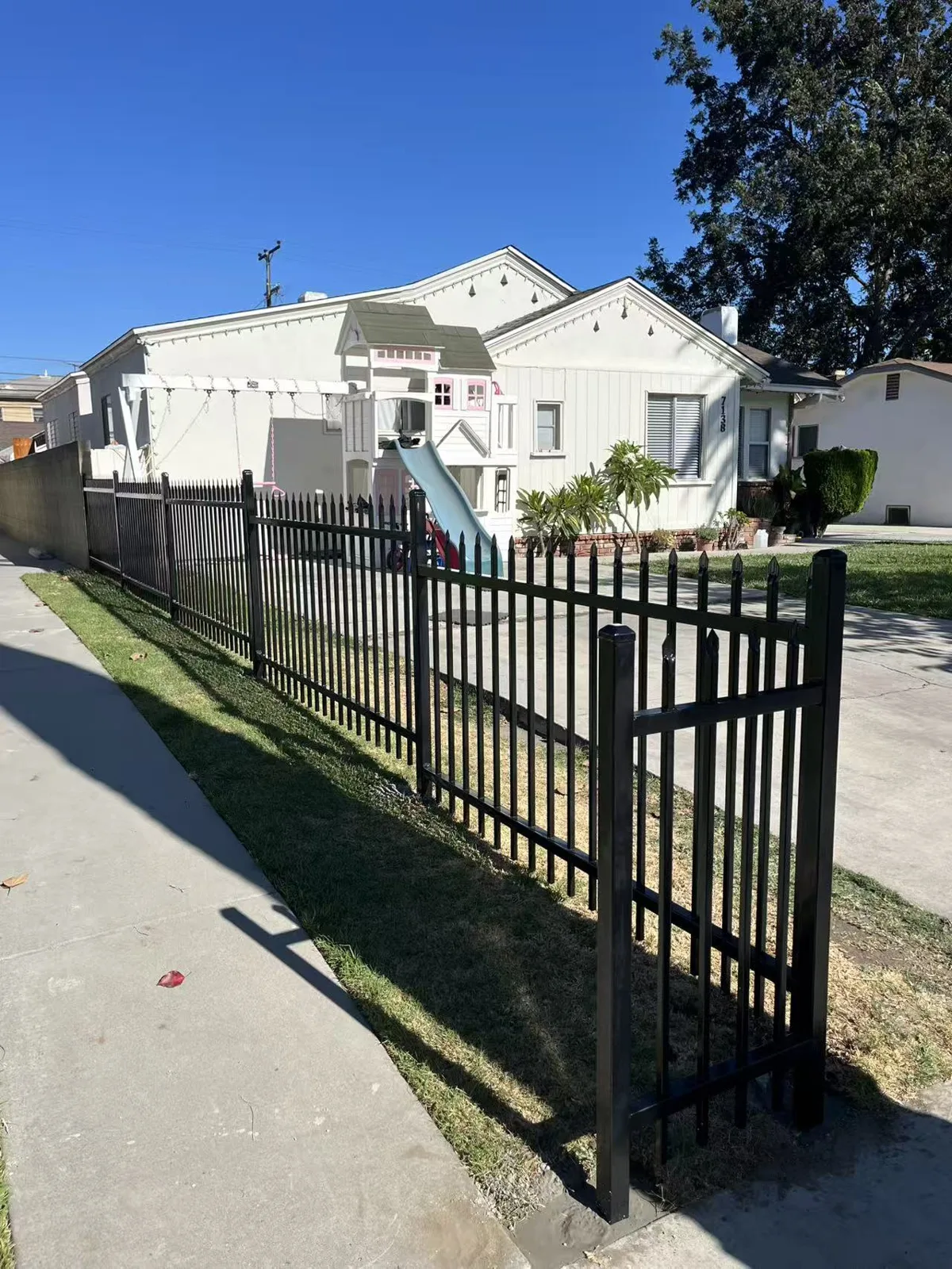 Black spike-top iron fence along a green front lawn with the home visible behind in Huntington Park, CA by Apexguard Fence