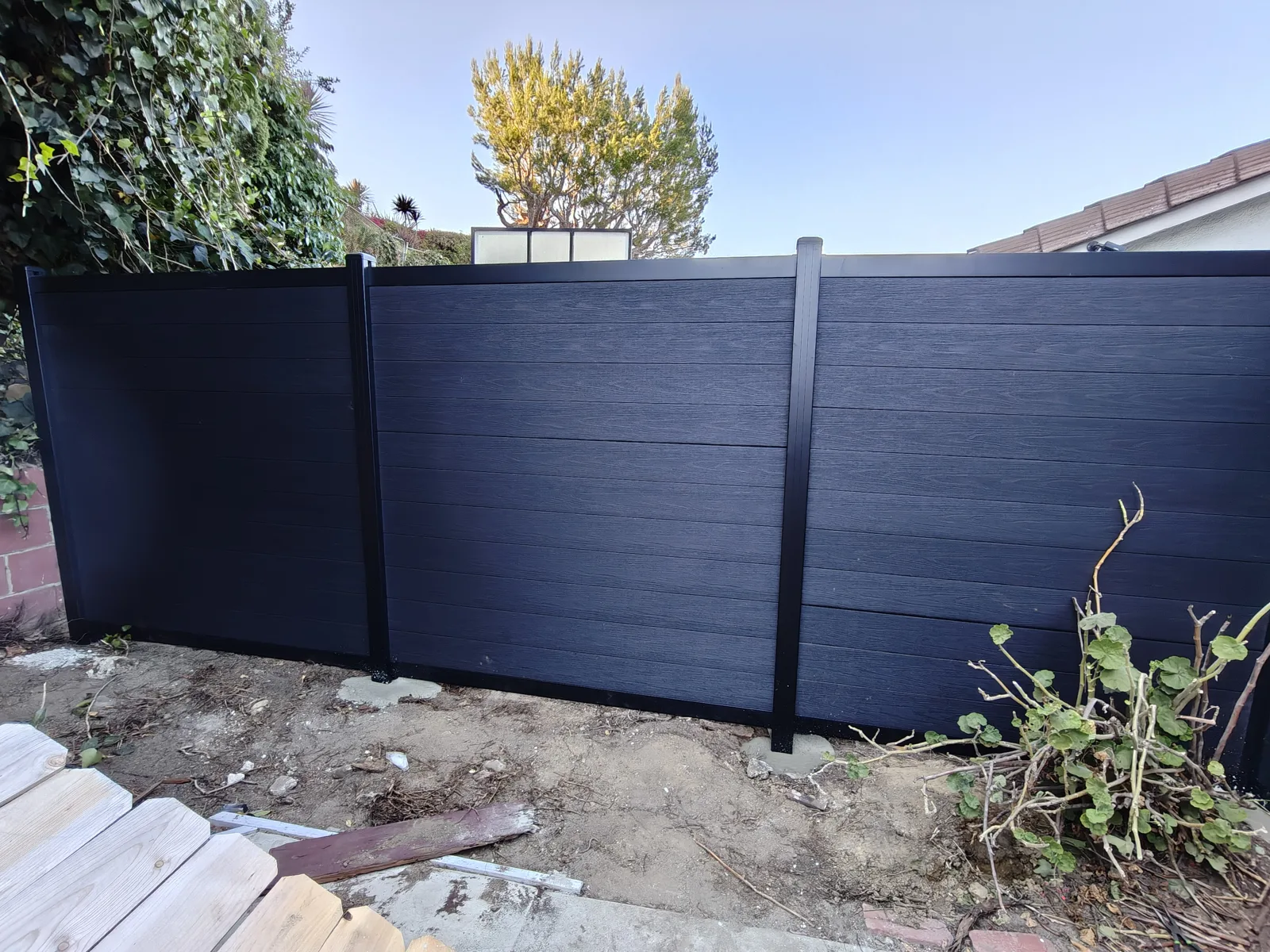 Charcoal composite WPC fence run replacing an old wood fence in Los Angeles