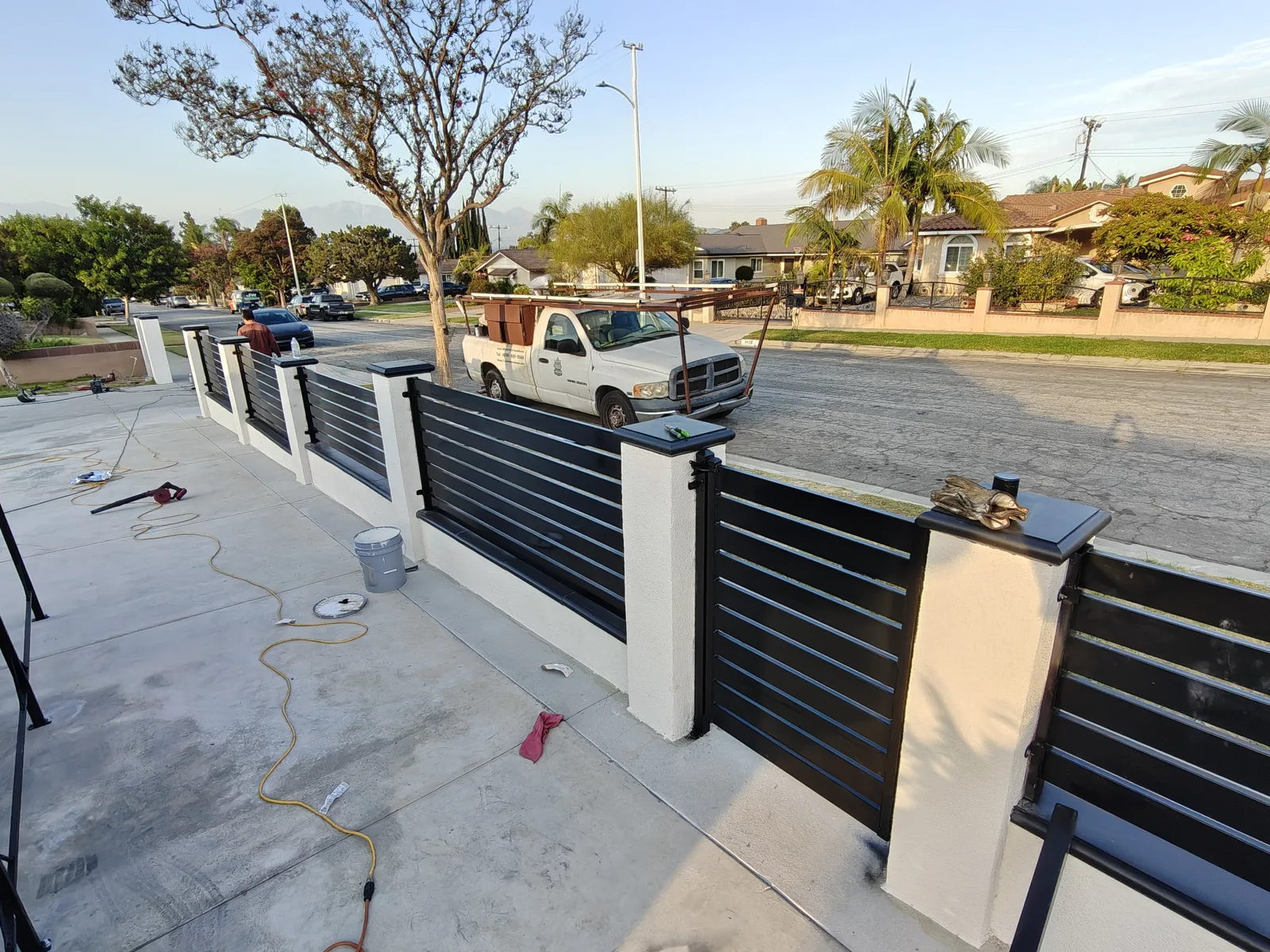 Corner view of modern CMU and horizontal slat fence wrapping two street frontages in La Puente, CA