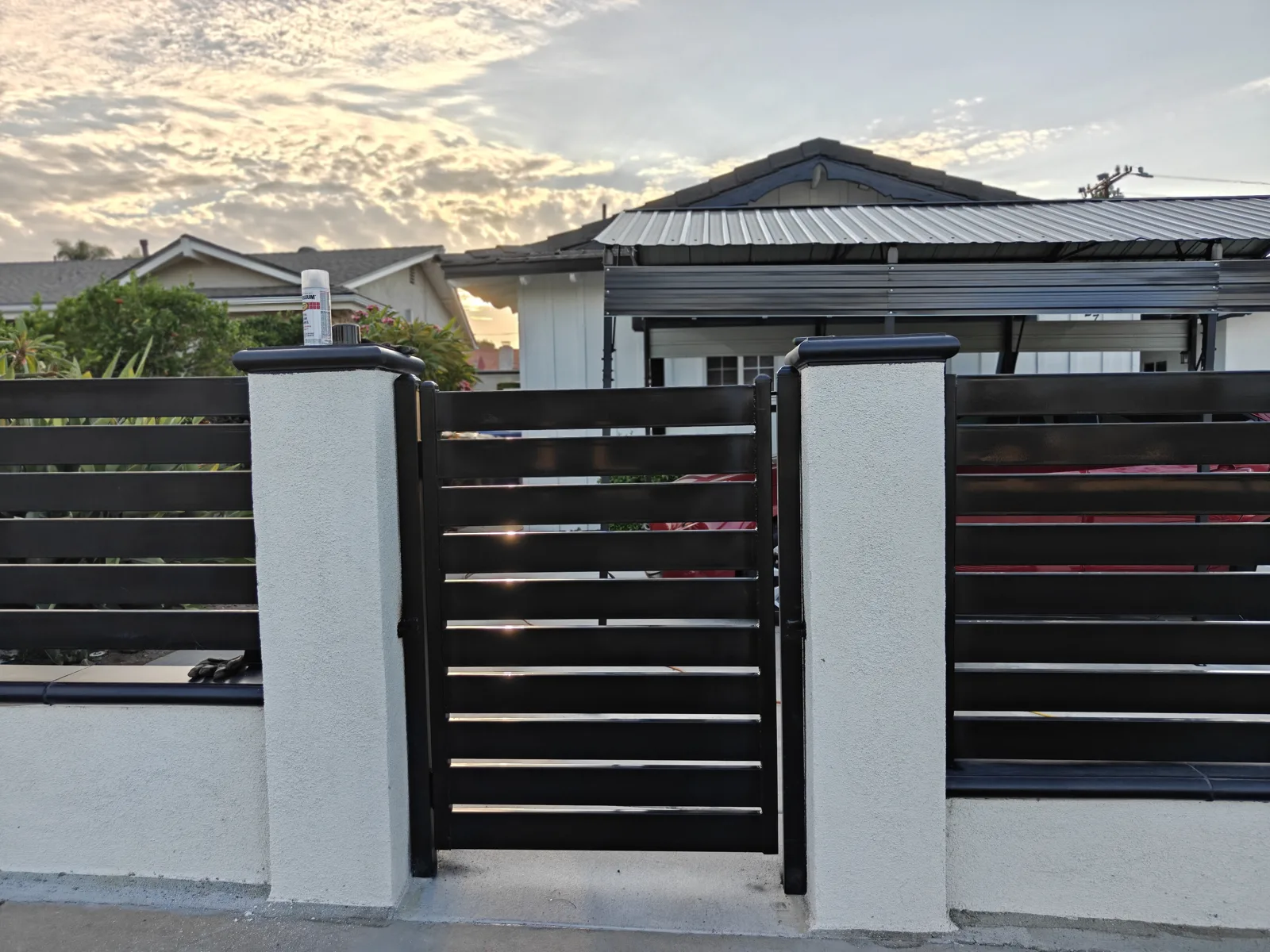 Matching black horizontal slat walk gate between white stucco pilasters — Apexguard Fence, La Puente, CA
