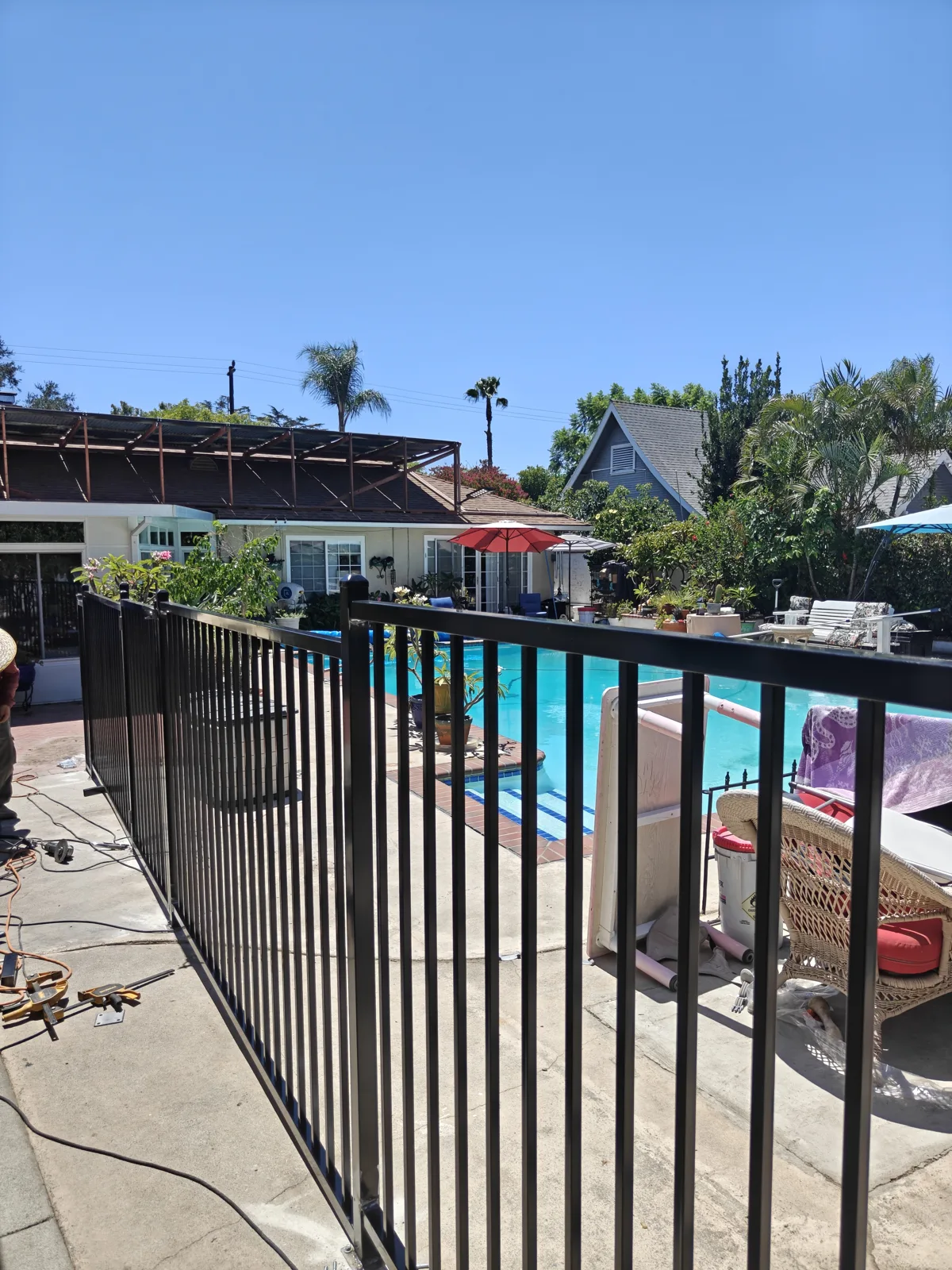 Black iron pool fence run with pool water behind — a real Apexguard Fence project in Ontario, the same build we install in Corona, CA