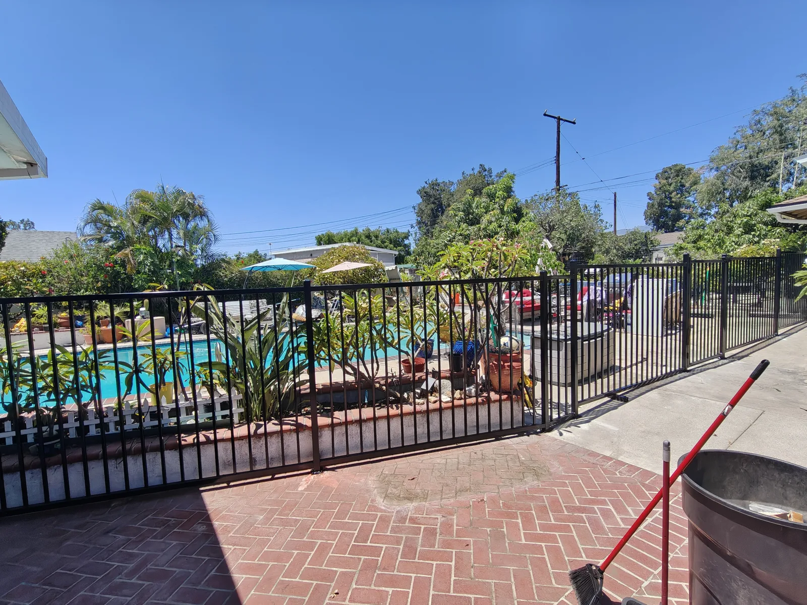 Black flat-top iron pool fence along a brick patio — a real Apexguard Fence project in Ontario, CA