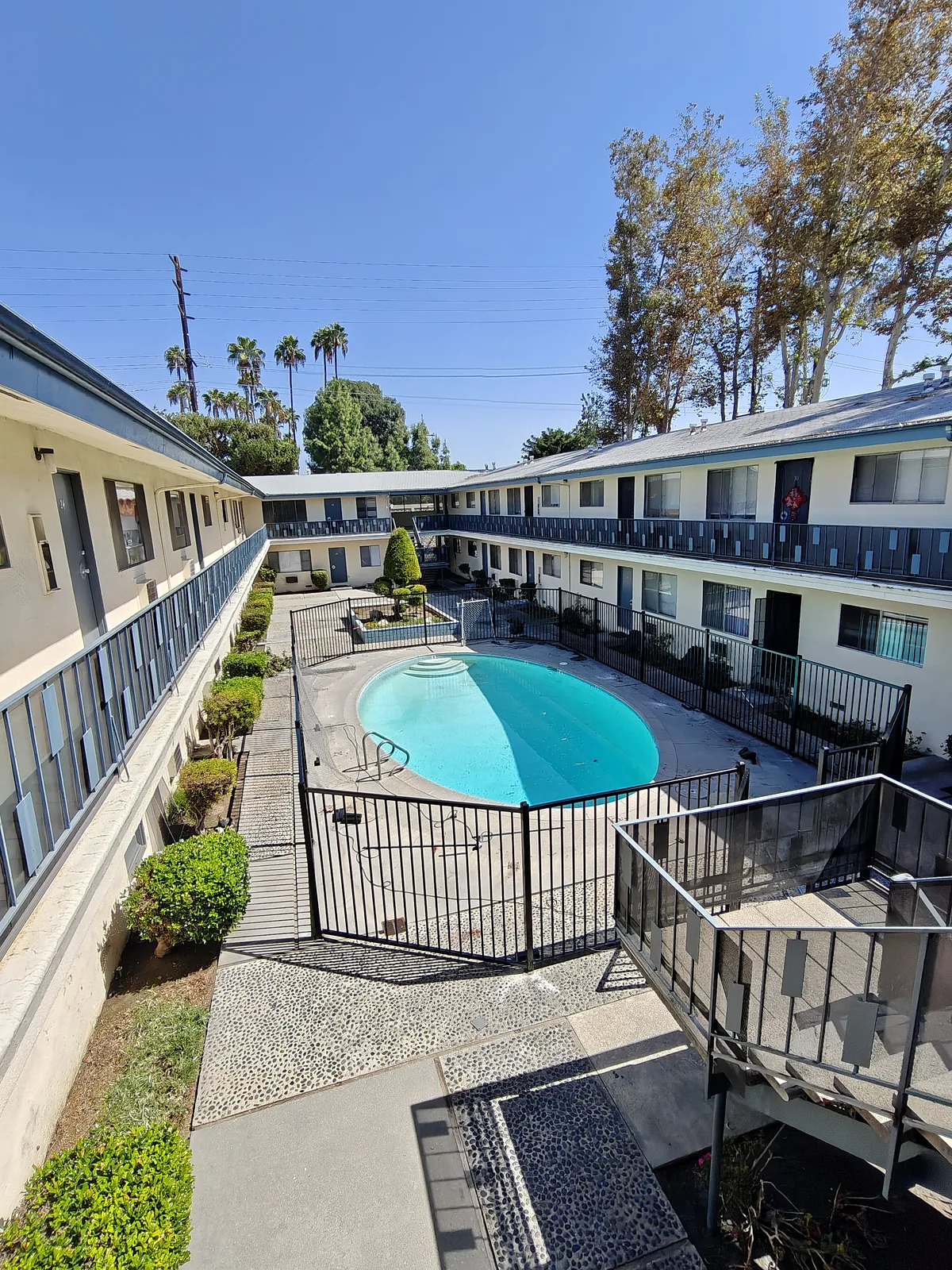 Black iron pool fence enclosing an apartment courtyard pool in West Covina, CA, seen from the second-floor balcony — a real Apexguard Fence project