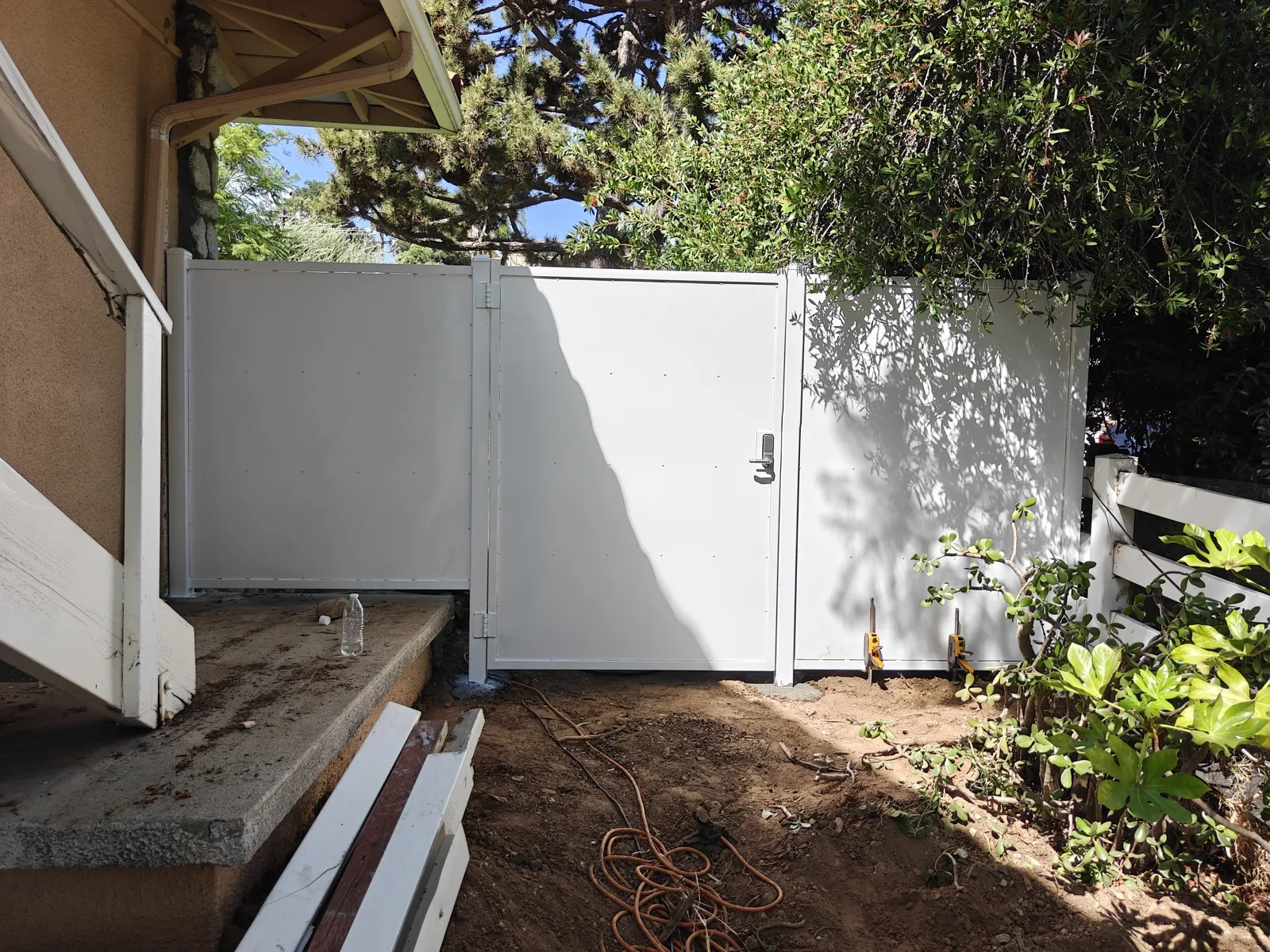White solid steel walk gate and privacy fence at a side entrance seen from the porch — a real Apexguard Fence project in West Covina, CA