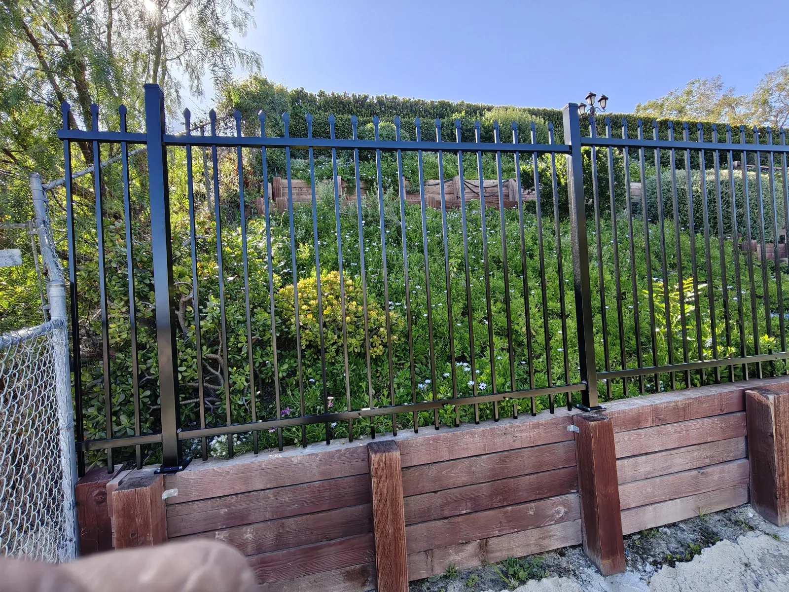 Front view of tight-spaced spear-top wrought iron pickets on a coyote fence in West Hills