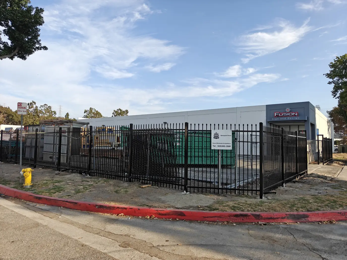 Completed 7 ft commercial spike-top steel security fence wrapping the corner of the Fusion Sign & Design yard in Whittier, CA by Apexguard Fence