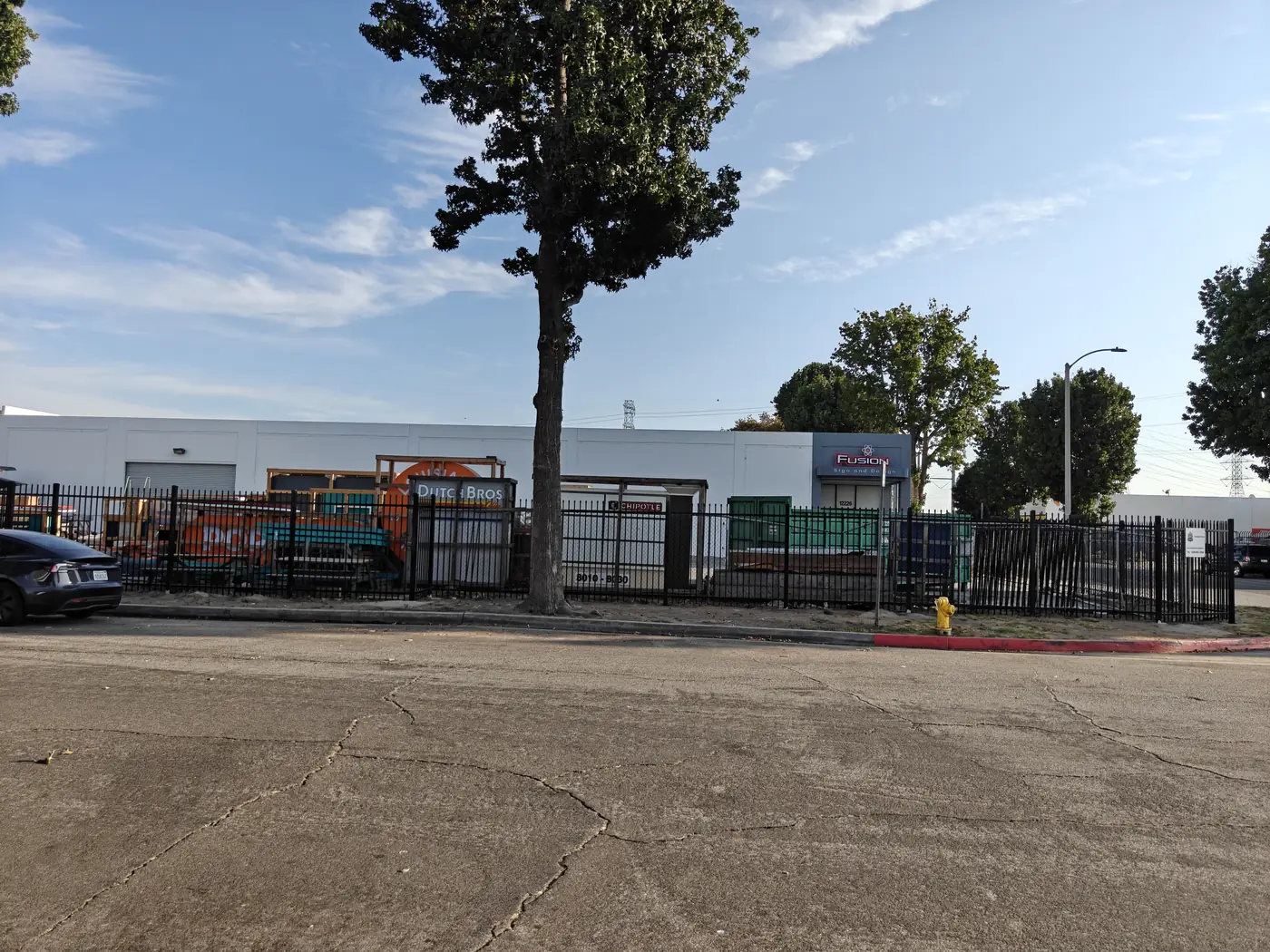 Street view of a completed 7 ft commercial spike-top steel fence along an industrial frontage in Whittier, CA