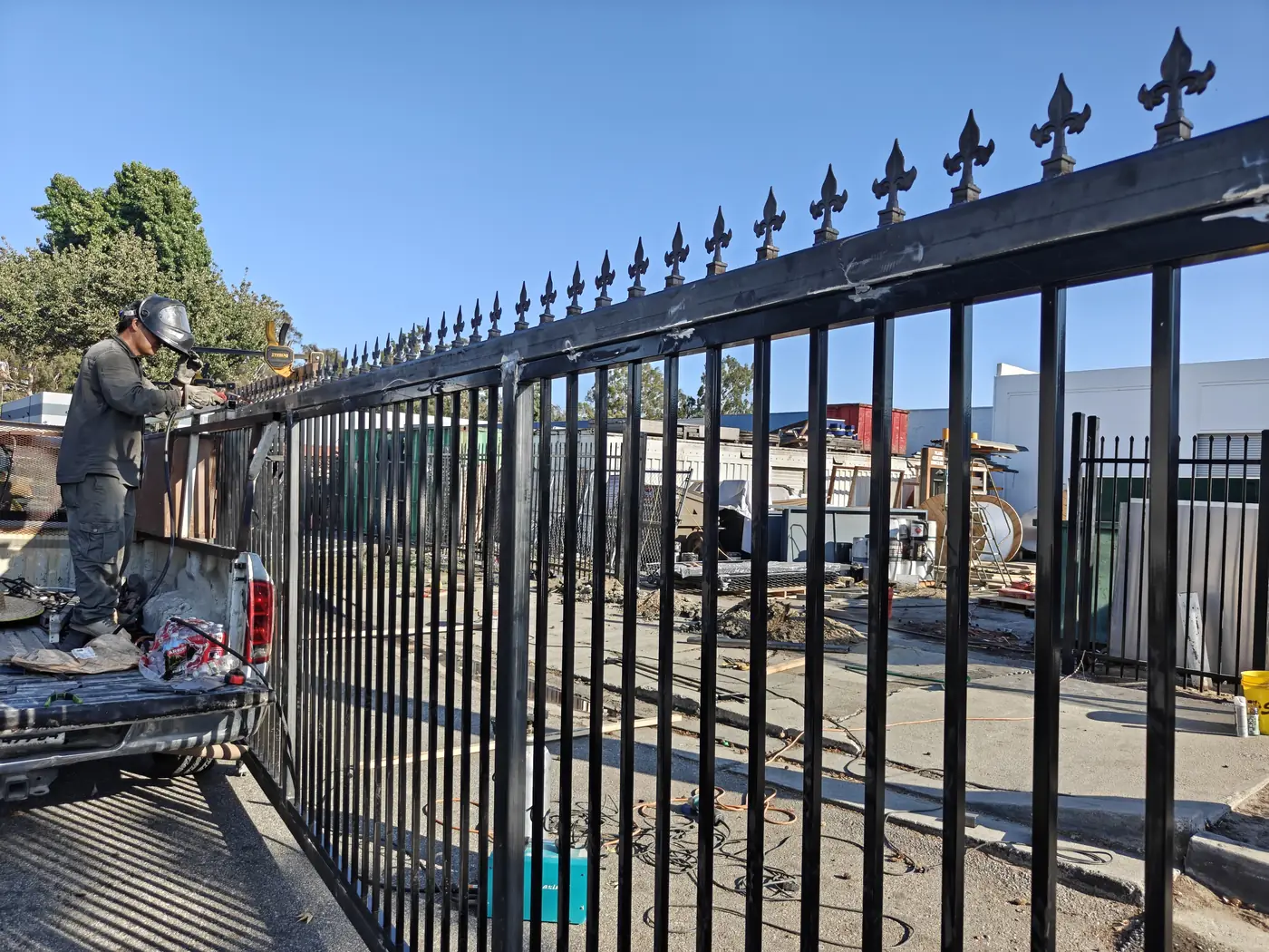Welding cast fleur-de-lis finials onto the top rail of a commercial steel swing gate in Whittier, CA