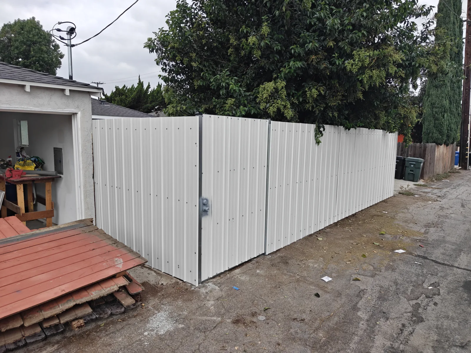 White corrugated steel privacy fence with integrated access door along an alley — a real Apexguard Fence project in Whittier, CA